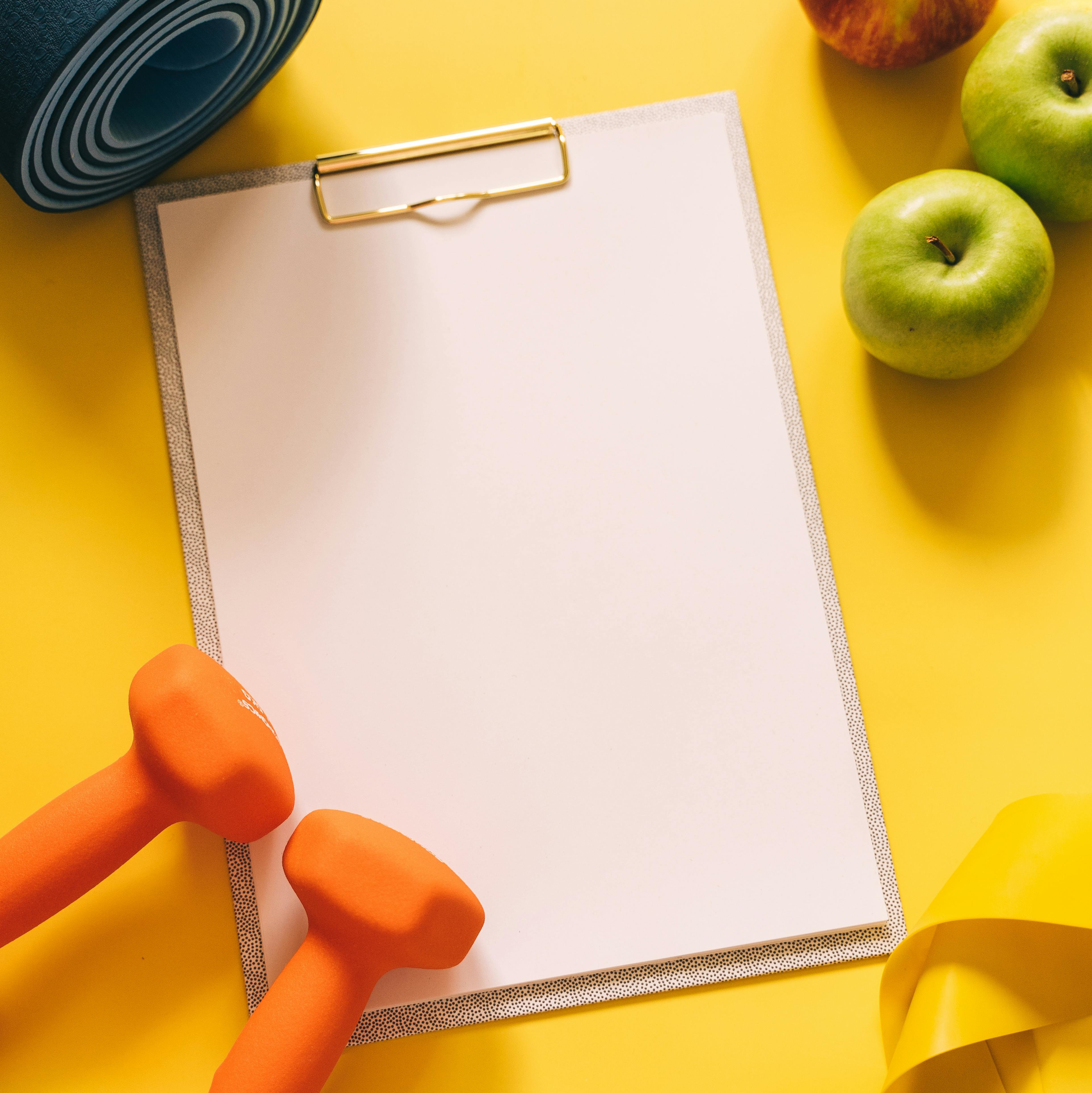 Blank clipboard surrounded by gym equipment